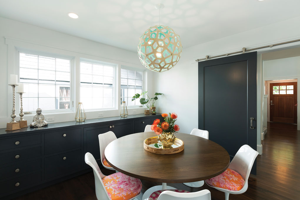 A dining room that features vibrantly-colored seats, a built-in storage area and sliding barn door that allows for privacy.