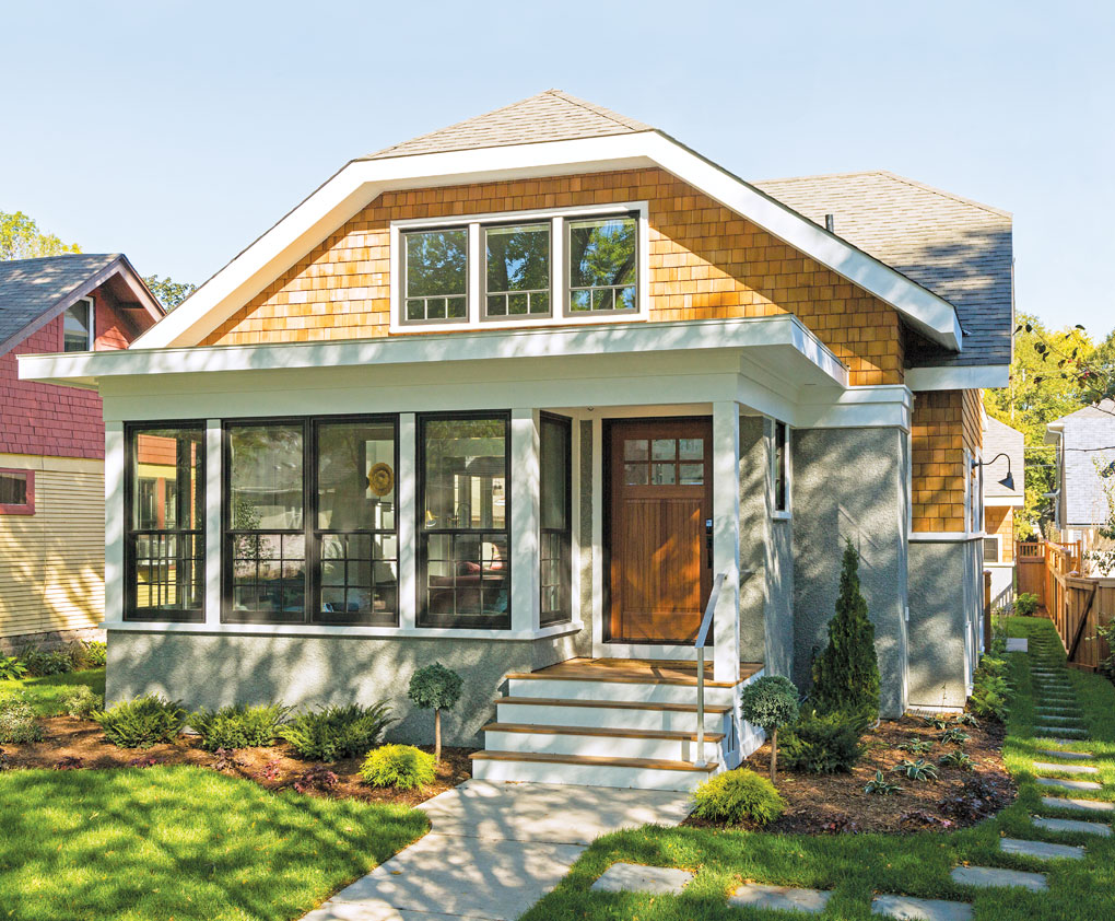 The facade of a bungalow-style home in St. Paul on a sunny day accented by green grass and landscaping.
