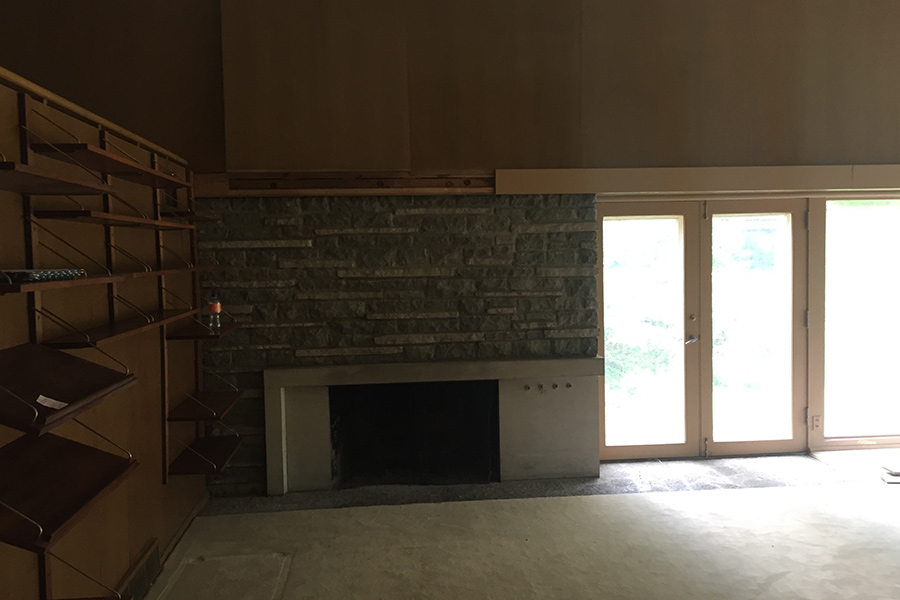 A "before" photo of a living room with a fireplace before it was remodeled by Bella Custom Homes.