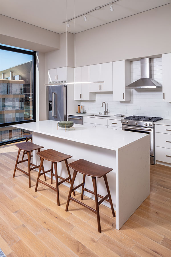 An all white kitchen with light wood flooring inside a room at 365 Nicollet, one of the stops on Midwest Home's 2018 Luxury Loft and Condo Tour.