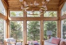 The existing home’s new 275-square-foot pine sunroom features a patterned sofa and powder blue cocktail table, a pair of 1960s French bamboo chairs, and a two-tiered chandelier in antique burnished brass that dangles overhead.