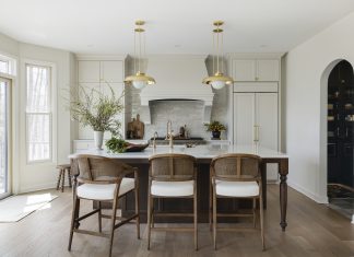 Packed with custom cabinetry, the kitchen is the heart of the home. The warm oak island, accented by Ormandy pendant lights from Rejuvenation, anchors the space and provides contrast with the walls and millwork, painted in Benjamin Moore’s creamy Swiss Coffee shade.