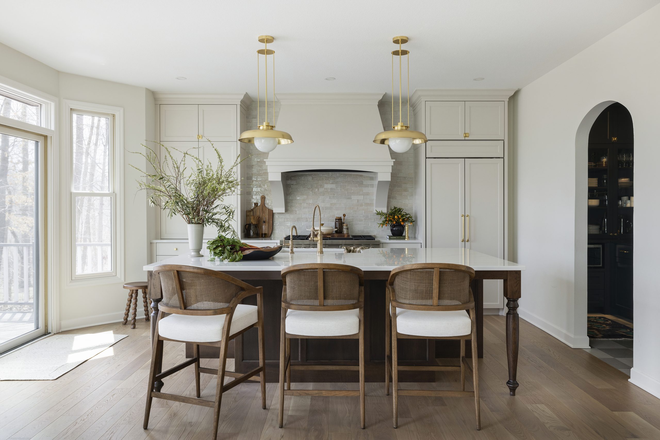 Packed with custom cabinetry, the kitchen is the heart of the home. The warm oak island, accented by Ormandy pendant lights from Rejuvenation, anchors the space and provides contrast with the walls and millwork, painted in Benjamin Moore’s creamy Swiss Coffee shade.