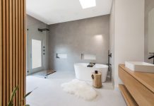 Large, minimalist bathroom with gray tiling, walk-in-shower, and freestanding bathtub.