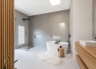 Large, minimalist bathroom with gray tiling, walk-in-shower, and freestanding bathtub.