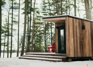 A snow covered cabin overlooking trees