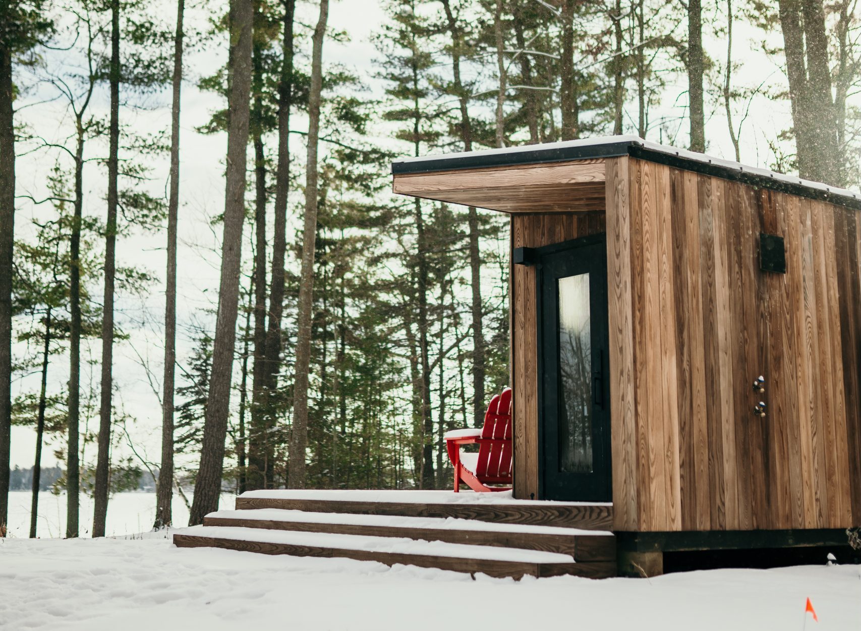 A snow covered cabin overlooking trees