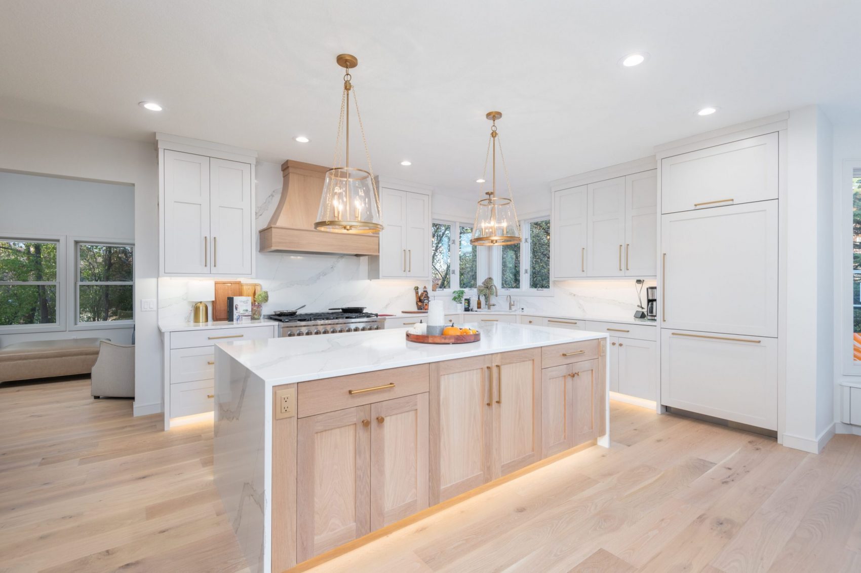 A kitchen interior with wood details shared across the open floorplan, cabinets, and even the stove hood demonstrating current flooring trends.