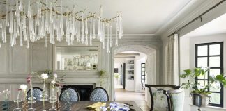 This Lake Minnetonka dining room featured in the O'Hara Interiors quiz has design elements like a statement chandelier, large wooden table, and colorful seating.