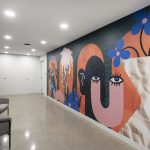 An apartment building hallway featuring a mural with graphic shapes and whimsical design with bold, bright colors.