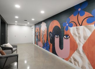An apartment building hallway featuring a mural with graphic shapes and whimsical design with bold, bright colors.