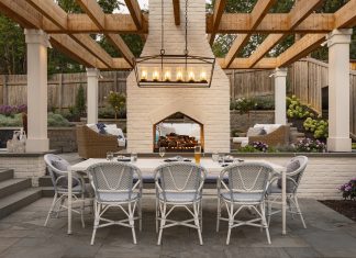 Beneath the dining table, a triple diamond inlay pattern in the patio tile subtly echoes the angled arch of the fireplace, as well as the linear design of the Hinkley chandelier hanging overhead.