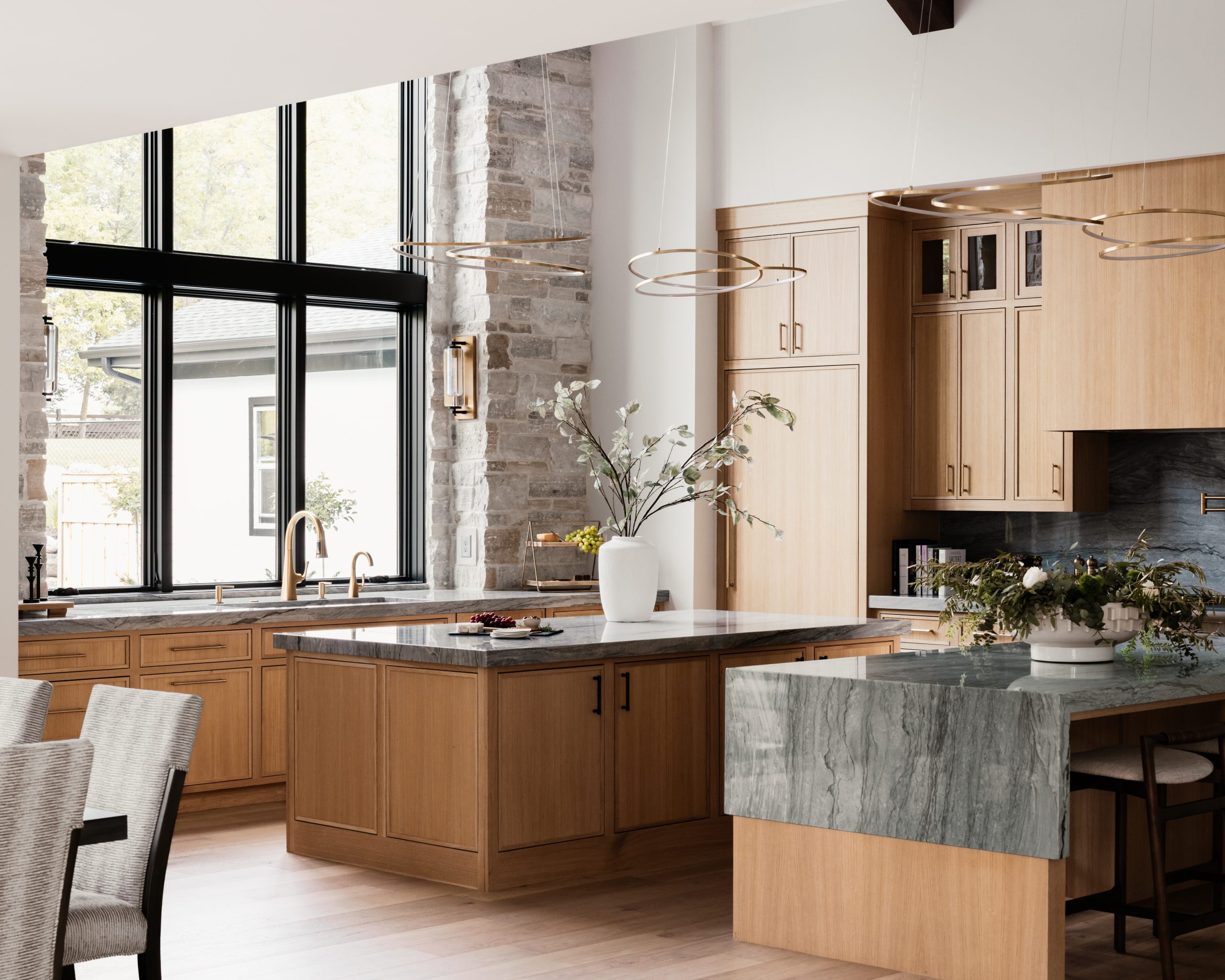 The chef’s-style kitchen features a spacious pantry and dual islands topped with quartzite, one with a unique half-waterfall countertop. 