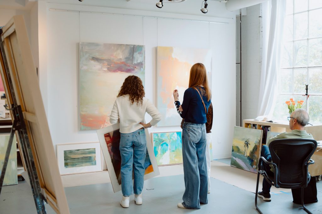 Visitors select paintings for sale at an Art-A-Whirl artist studio
