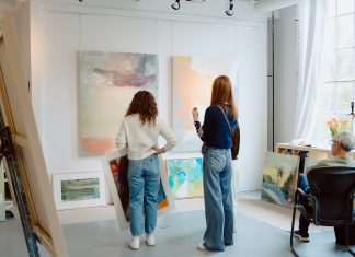 Visitors select paintings for sale at an Art-A-Whirl artist studio