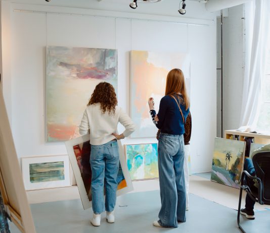 Visitors select paintings for sale at an Art-A-Whirl artist studio